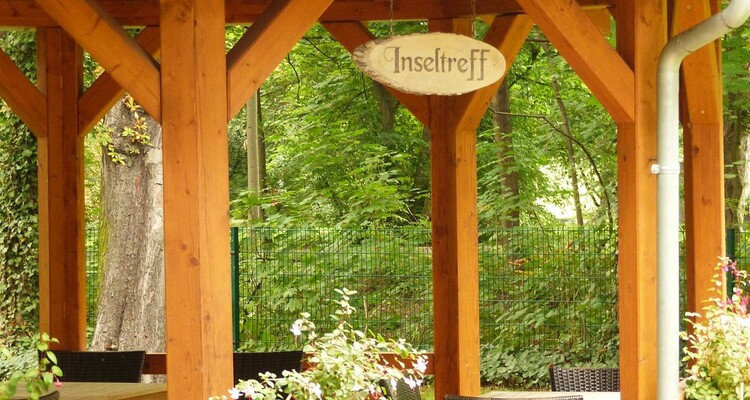 Pavillion im Garten aus Holz mit dem Schriftzug Inseltreff.